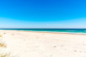 A beach with clear skies and calm waters. - Good Company - Classic 3BR Oceanfront Beach Cottage with Screen Porch (Topsail Beach)
