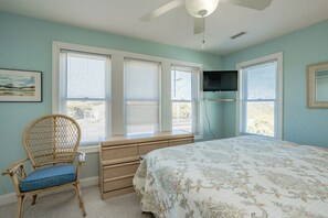 A bedroom with a bed, a chair, a dresser, and a television. - Good Company - Classic 3BR Oceanfront Beach Cottage with Screen Porch (Topsail Beach)