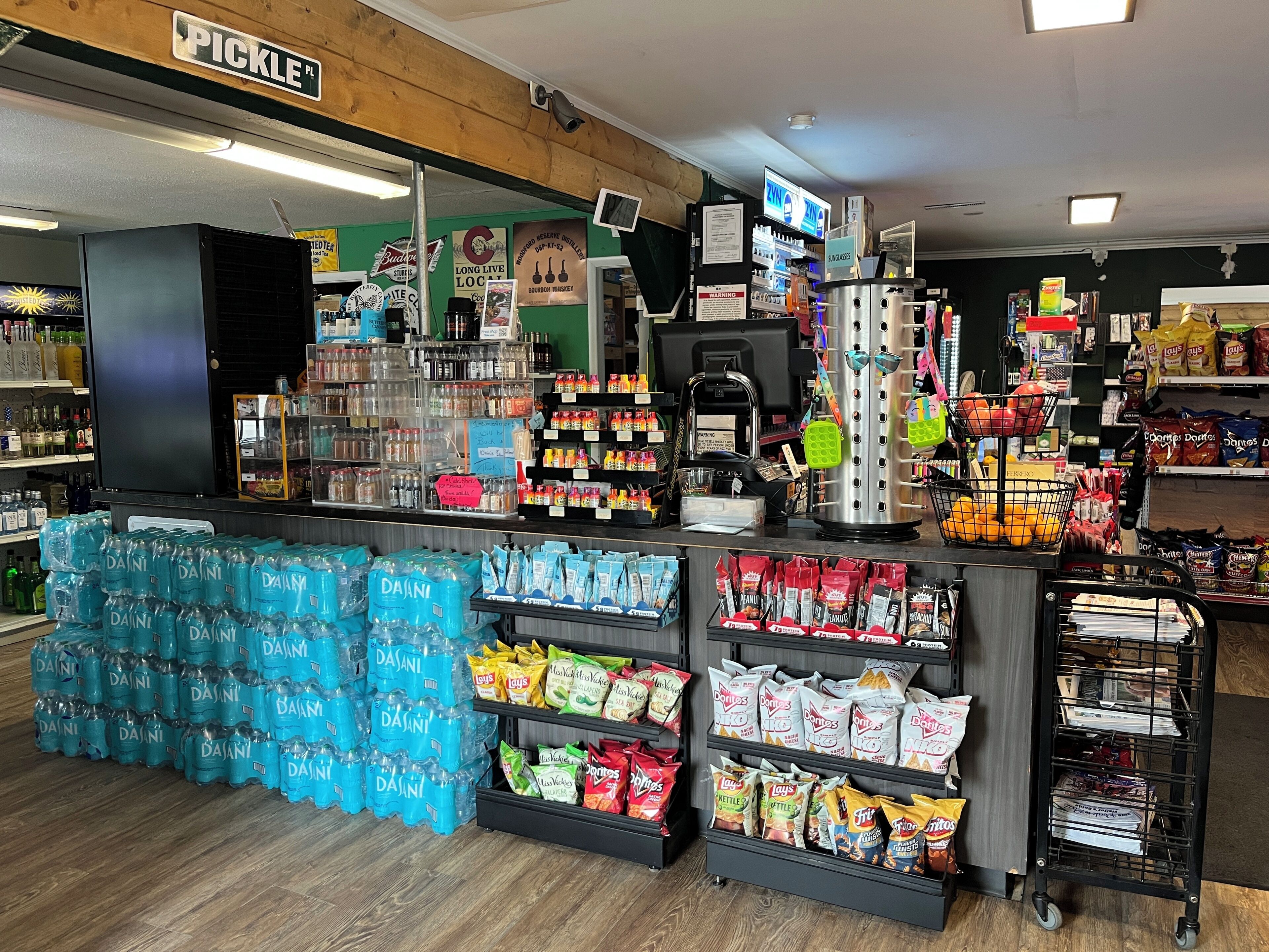 A store with a variety of snacks, bottled water, and a cash register.