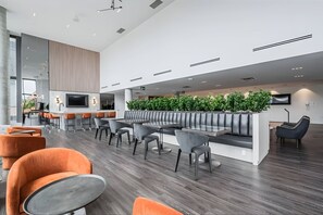 A modern lobby with a reception desk, seating areas, and a large screen. - Newly Built Modern Condo With Stunning City Views (Kitchener)