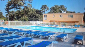 Un espace piscine avec des chaises longues bleues et un bâtiment en arrière-plan.