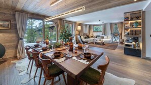 Un vaste espace de vie agrémenté d’un plafond en bois, d’une table à manger pouvant accueillir six personnes et d’un coin salon confortable.