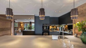 Une cuisine moderne dotée d’un îlot central, de luminaires suspendus et donnant sur l’espace de vie.