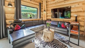 A cozy log cabin interior with a sectional sofa, a wooden coffee table, a zebra-patterned rug, and a TV mounted on the wall. - Vacation log cabin Black Forest 2 - Luxury chalet with sauna & whirlpool on the Feldberg (Feldberg (Schwarzwald))