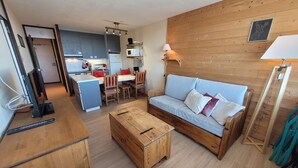 A compact living space with a kitchenette, a sofa, a dining table, and a wooden coffee table. - Comfortable apartment, ski-in ski-out, pets allowed (Plagne Aime 2000)