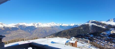 Blick auf Berge mit schneebedeckten Gipfeln und einem Skiort darunter.