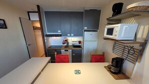 A compact kitchen with a white countertop, a microwave, a coffee maker, and a red chair. - Comfortable apartment, ski-in ski-out, pets allowed (Plagne Aime 2000)