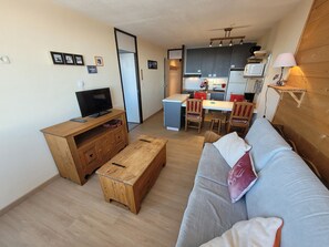 A compact living space with a sofa, wooden coffee table, TV, kitchenette, and a dining area. - Comfortable apartment, ski-in ski-out, pets allowed (Plagne Aime 2000)