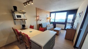 A compact kitchen with a dining area, a sofa, and a view of the outdoors. - Comfortable apartment, ski-in ski-out, pets allowed (Plagne Aime 2000)