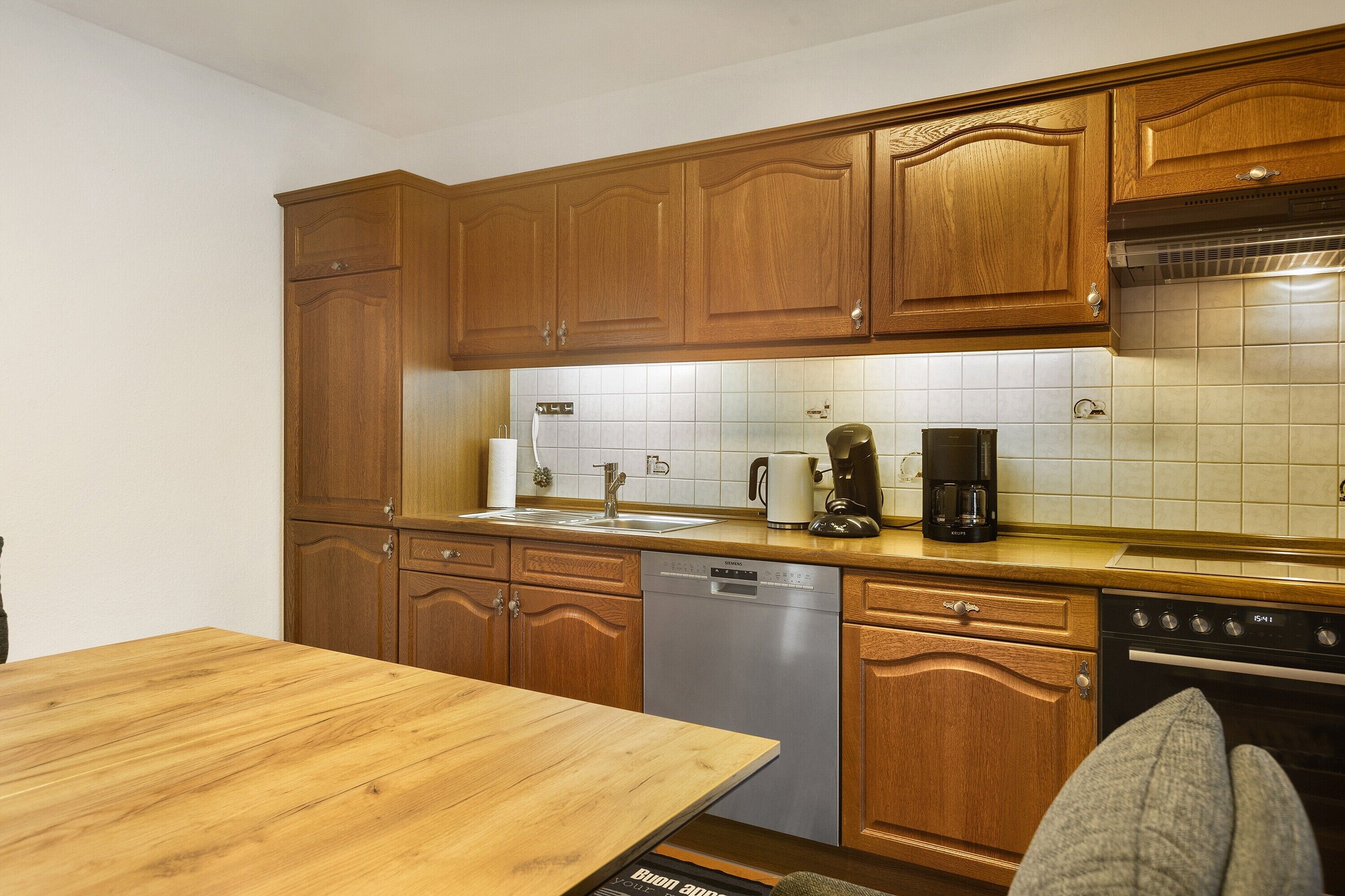 A kitchen with wooden cabinets, a dishwasher, a coffee maker, and a stove.