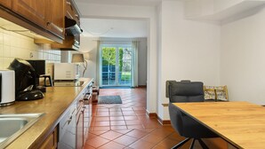 Una cocina moderna con armarios de madera, una mesa de comedor y vistas a un espacio exterior verde.