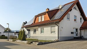 Una casa de dos plantas con techo inclinado, paneles solares y garaje.