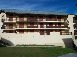A multi-story building with balconies, a flat roof, and a grassy area in front. - 2-room south-facing apartment for 4 in Valloire (Valloire)