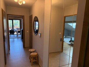 A hallway with a dining area, a mirror, and a bedroom with a bed. - New apt 3 br 8 ppl near rink with balcony and parking (Arâches-la-Frasse)