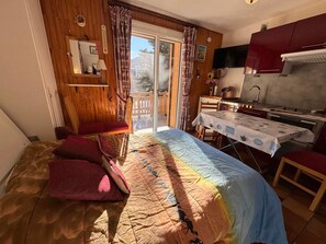 A cozy room with a bed, a small table, and a kitchen area. - Cozy apartment near slopes and shops with terrace (Vars)