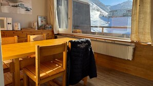 Ein Essbereich aus Holz mit einem großen Fenster mit Blick auf eine verschneite Berglandschaft.