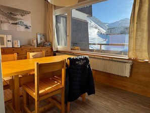 A wooden dining area with a large window overlooking a snowy mountain landscape. - Functional ski-in/ski-out apartment with balcony in Tignes (Tignes)