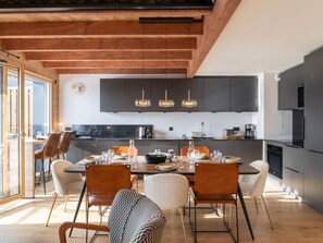 A modern kitchen with dark cabinets, a central island, and pendant lighting. - Spacious apartment for 8 people, mountain view, Wi-Fi, parking (Huez)