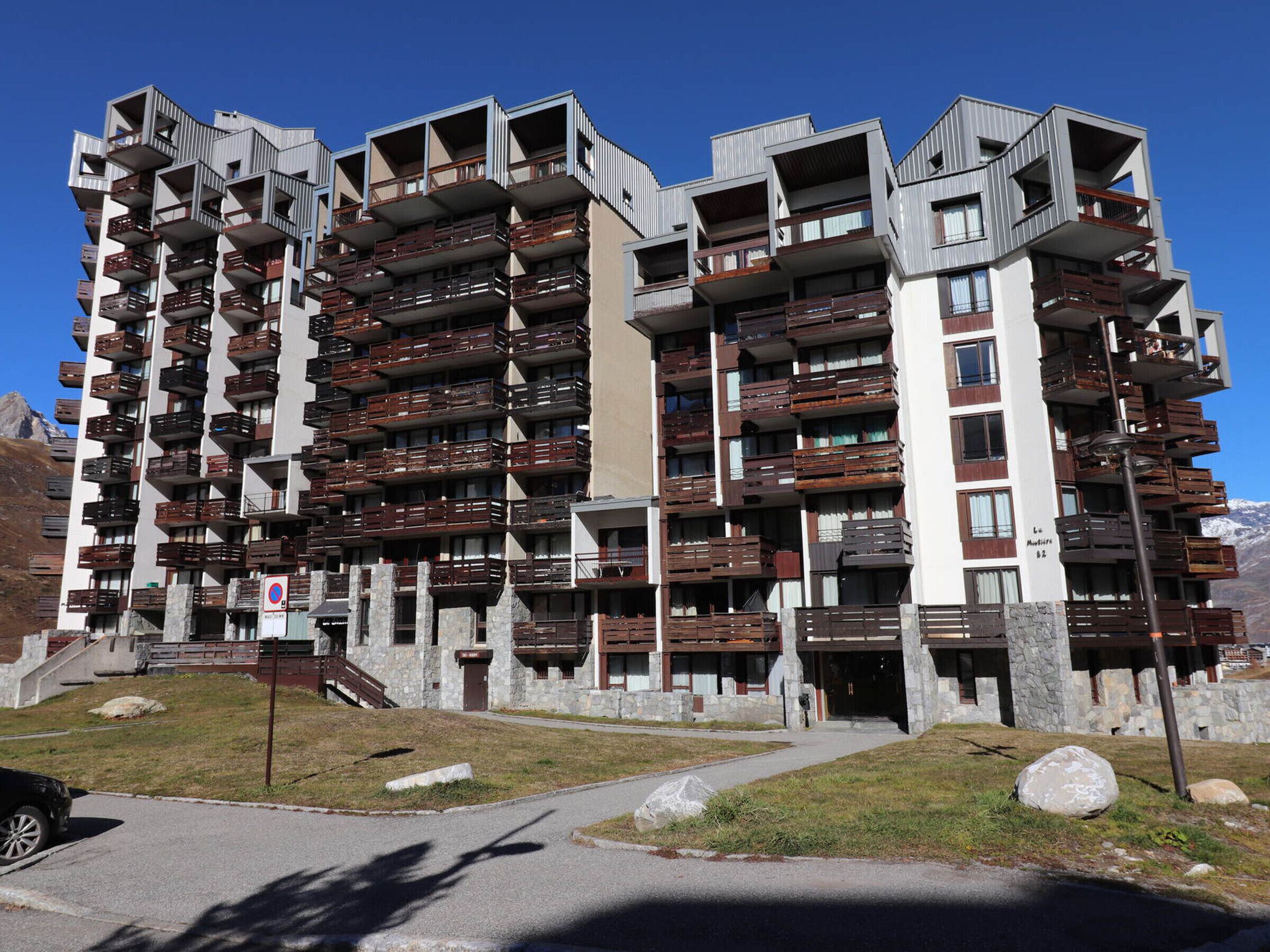 Un hotel a più piani con balconi, facciata in pietra e vista chiara sulle montagne sullo sfondo.
