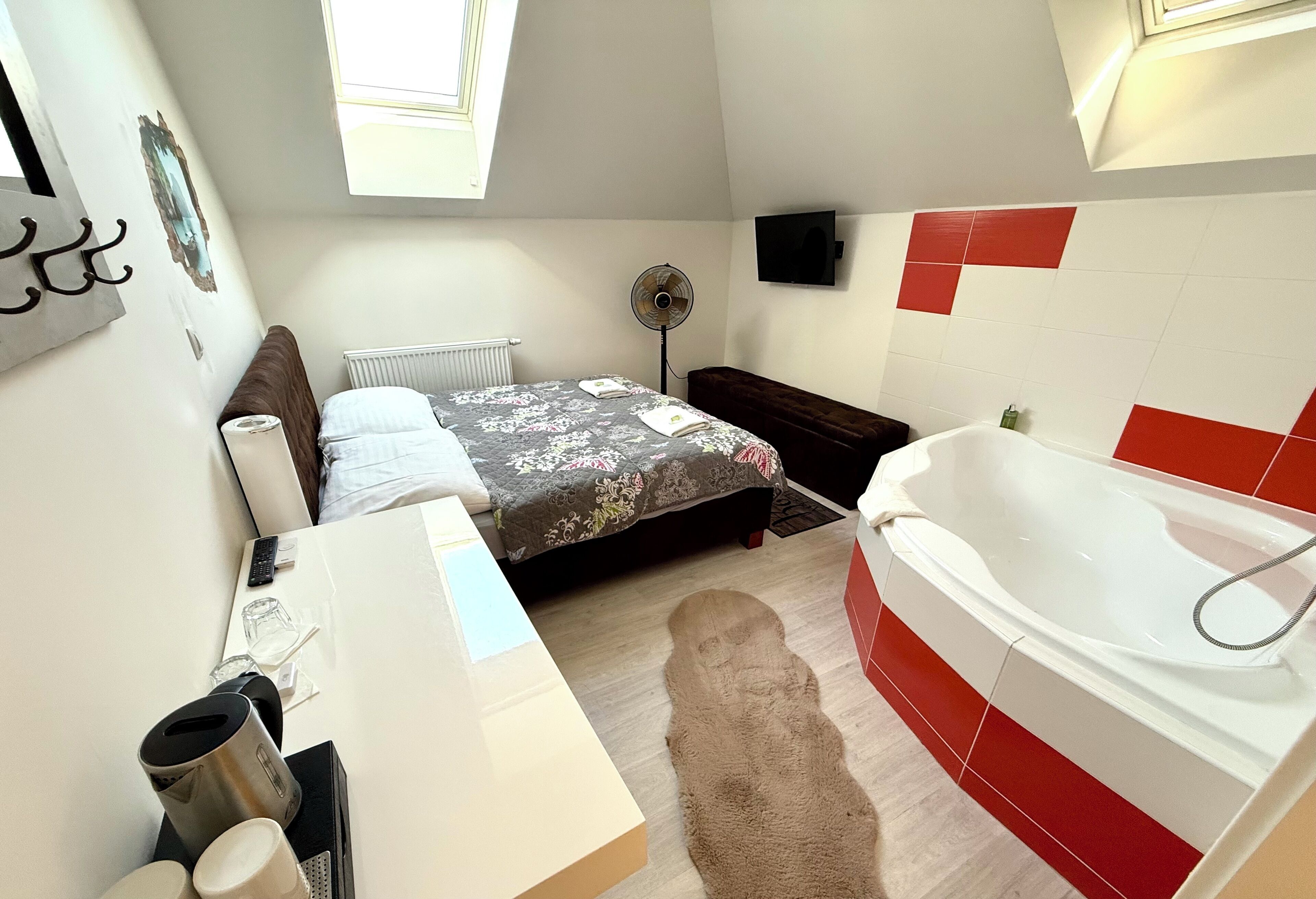 Een slaapkamer met een bed, nachtkastje en een groot raam.