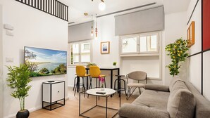Un salon moderne avec un canapé, une table à manger et des chaises, un téléviseur et une plante en pot.