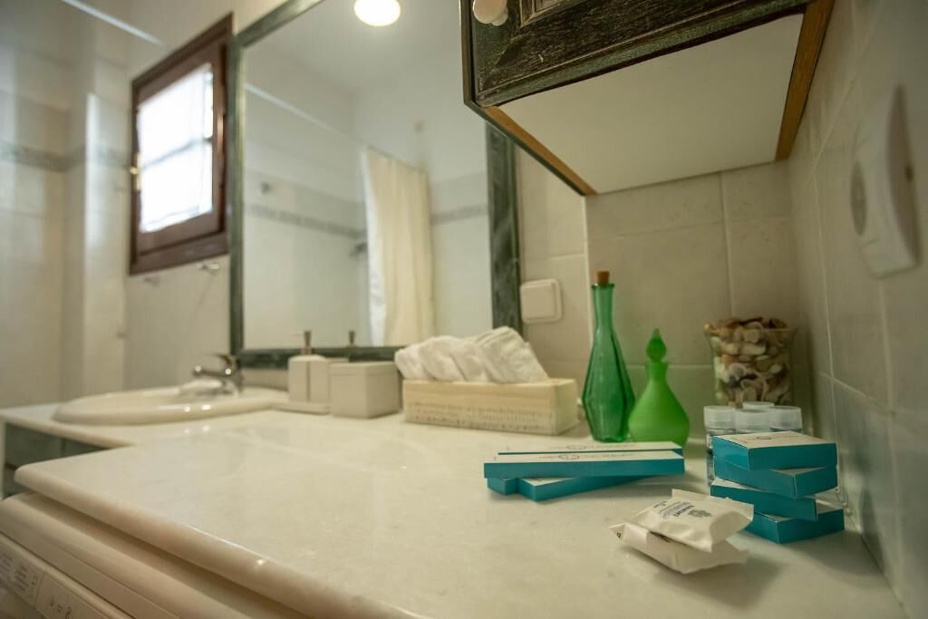 A bathroom with two sinks, a mirror, a window, and toiletries on the counter.