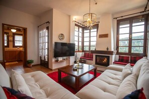 A living room with a fireplace, a television, and a sofa. - Alonia Forest House - Limni Plastira Getaway (Lake Plastiras)