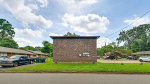 A small brick building with a flat roof, surrounded by a grassy area and parked cars. - The Homestead Luxury Cozy 2BR Apartment in Nacogdoches Near SFA University and Downtown Pet Friendly Business Ready Extended Stays Welcome With Self Check In High Speed Wifi Full Kitchen In Unit Laundry Private Parking and Quiet Comfort (Nacogdoches)