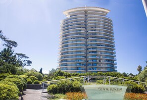 Ein hohes, zylindrisches Hotel mit zahlreichen Balkonen und einem Schild mit der Aufschrift 'SEA & FOREST'.