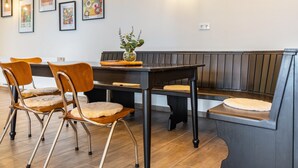 A dining area with a wooden table, chairs, a bench, and framed artwork on the wall. - Suites at the Historic Berghotel Theresia (Eslohe (Sauerland))
