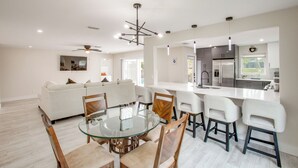 A modern kitchen with a central island, a dining area with a glass table, and a living area with a sofa. - Fishing Dock & Pool: Waterfront Cape Coral Retreat (Cape Coral)
