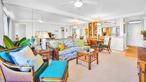 A living room with a sofa, chairs, a coffee table, and a dining area with a table and chairs. - Oceanfront Royal Mauian #515 - 2BR/2BA with Panoramic Views Near Kamaole Beaches (Kihei, Maui)