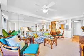 A living room with a sofa, chairs, a coffee table, and a dining area with a table and chairs. - Oceanfront Royal Mauian #515 - 2BR/2BA with Panoramic Views Near Kamaole Beaches (Kihei, Maui)