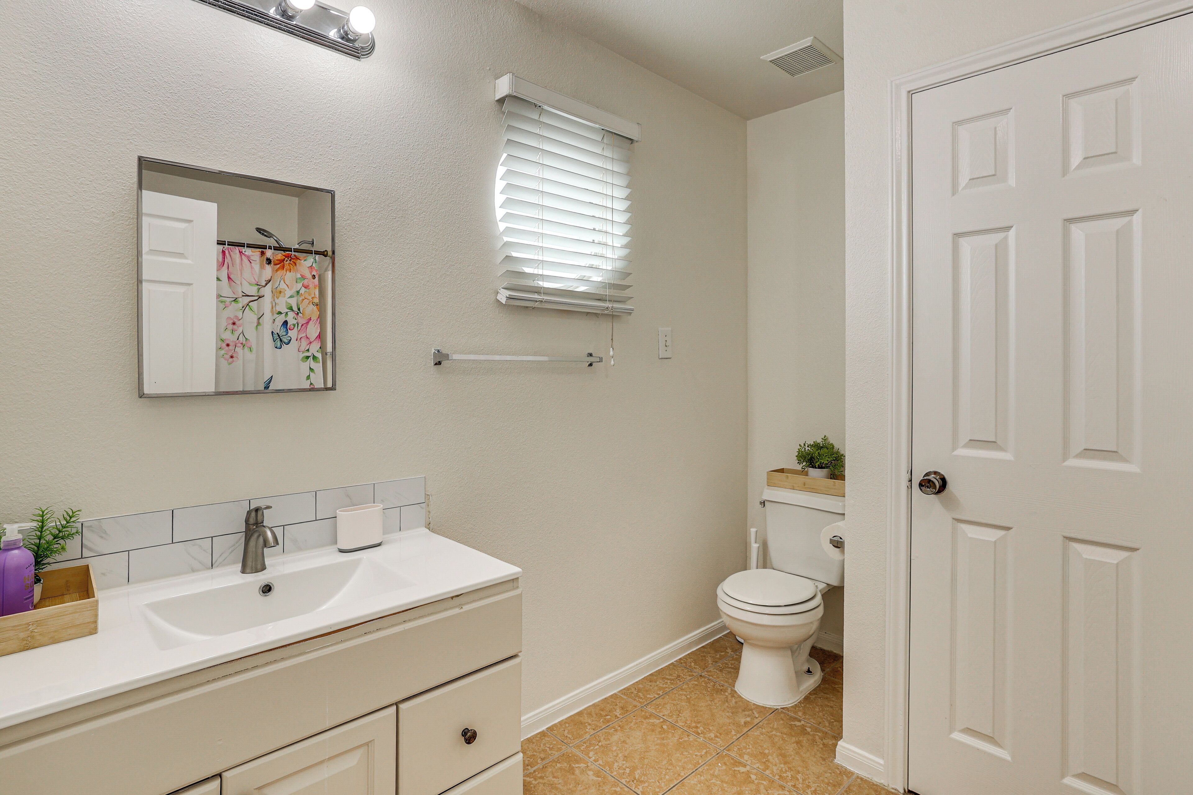 A bathroom with a white sink, mirror, and toilet.