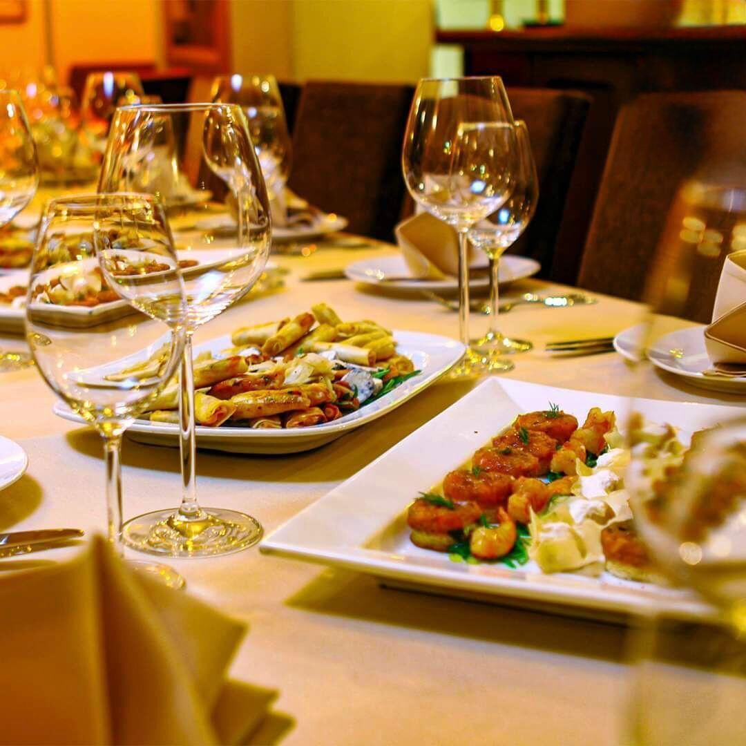 A dining table set with plates of food and wine glasses.