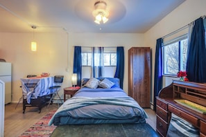 A bedroom with a bed, a desk, a chair, a window with curtains, and a ceiling fan. - 5 Mi to Coors Field & Lodo: North Denver Studio (Denver)