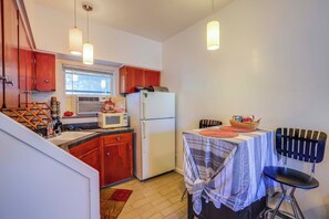 A compact kitchen with wooden cabinets, a refrigerator, a microwave, and a dining area with a table and chairs. - 5 Mi to Coors Field & Lodo: North Denver Studio (Denver)