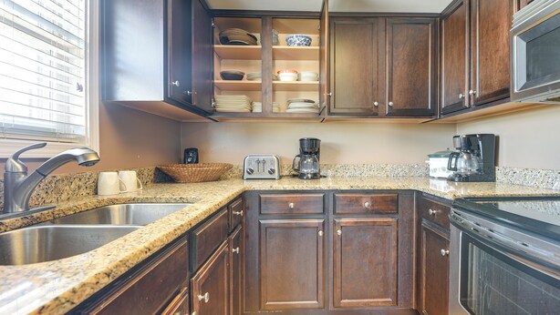 A kitchen with granite countertops, wooden cabinets, a built-in dishwasher, and a coffee maker. - Walk to Shore! Quiet Escape in North Myrtle Beach (North Myrtle Beach)