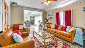 A spacious living room with leather sofas, a glass coffee table, and a ceiling fan.