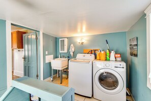 A laundry room with a washing machine, dryer, and various cleaning supplies. - Walk to Lake Ontario & Parks! Lovely Apartment (Oswego)