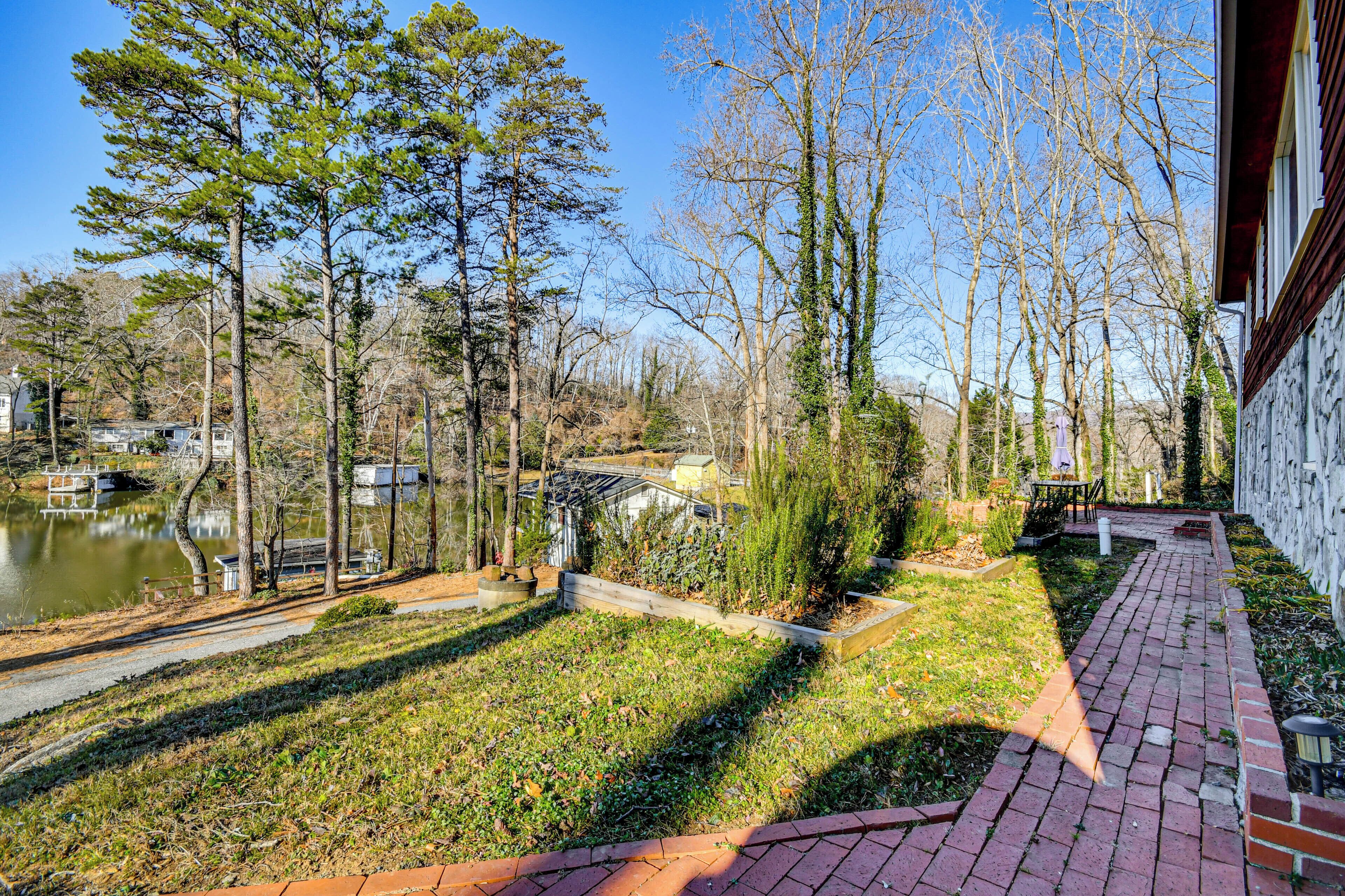 A courtyard with a brick pathway, a small pond, and trees.