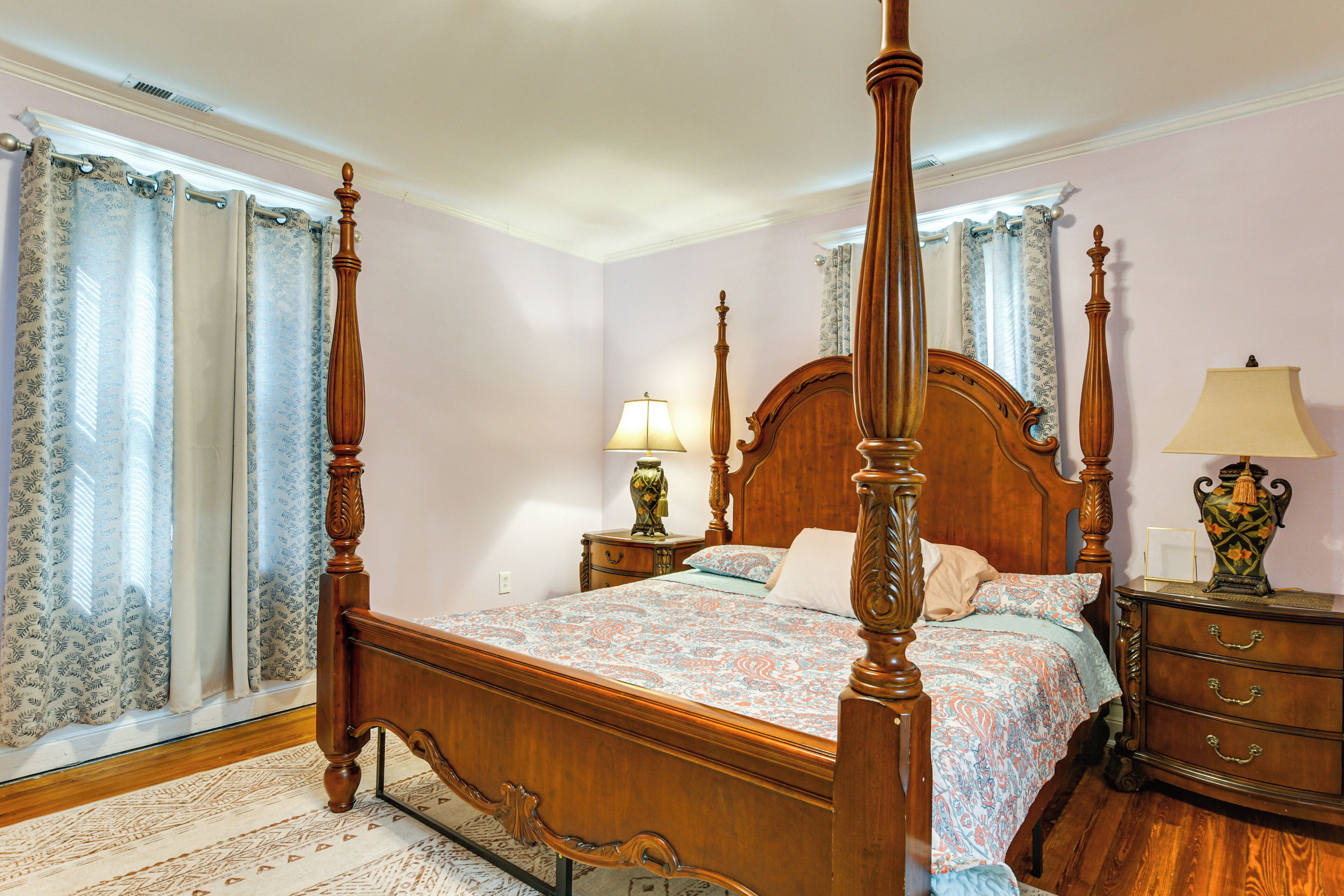 A four-poster bed with a wooden frame, a matching nightstand, and a dresser with drawers.