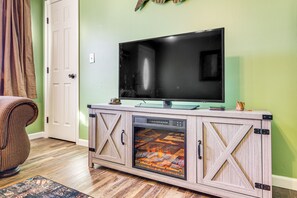 A living room with a flat-screen TV on a wooden cabinet, a fireplace, and a door with a curtain. - Lebanon Fishing Retreat w/ Fire Pit: Pets Welcome! (Lebanon)