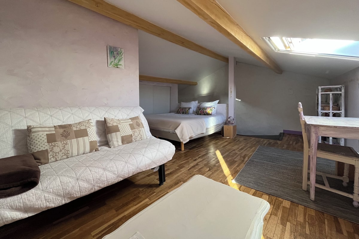Un dormitorio acogedor con cama, sofá, una mesita y una silla.