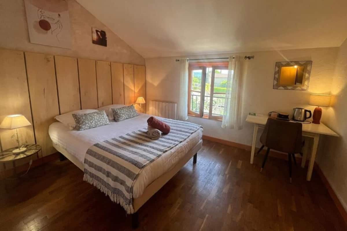 Un dormitorio con cama, escritorio, silla, ventana con cortinas y radiador.