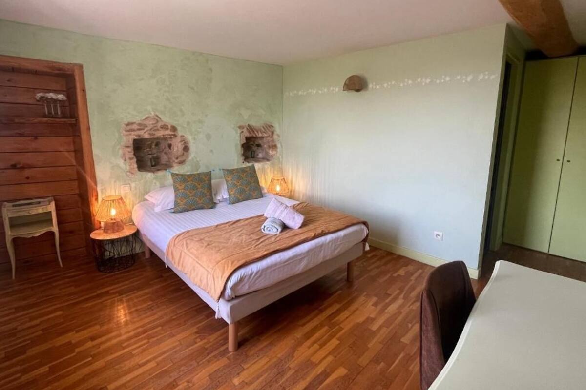 Un dormitorio con una cama de madera, dos lámparas de noche, una mesita pequeña y un armario verde.