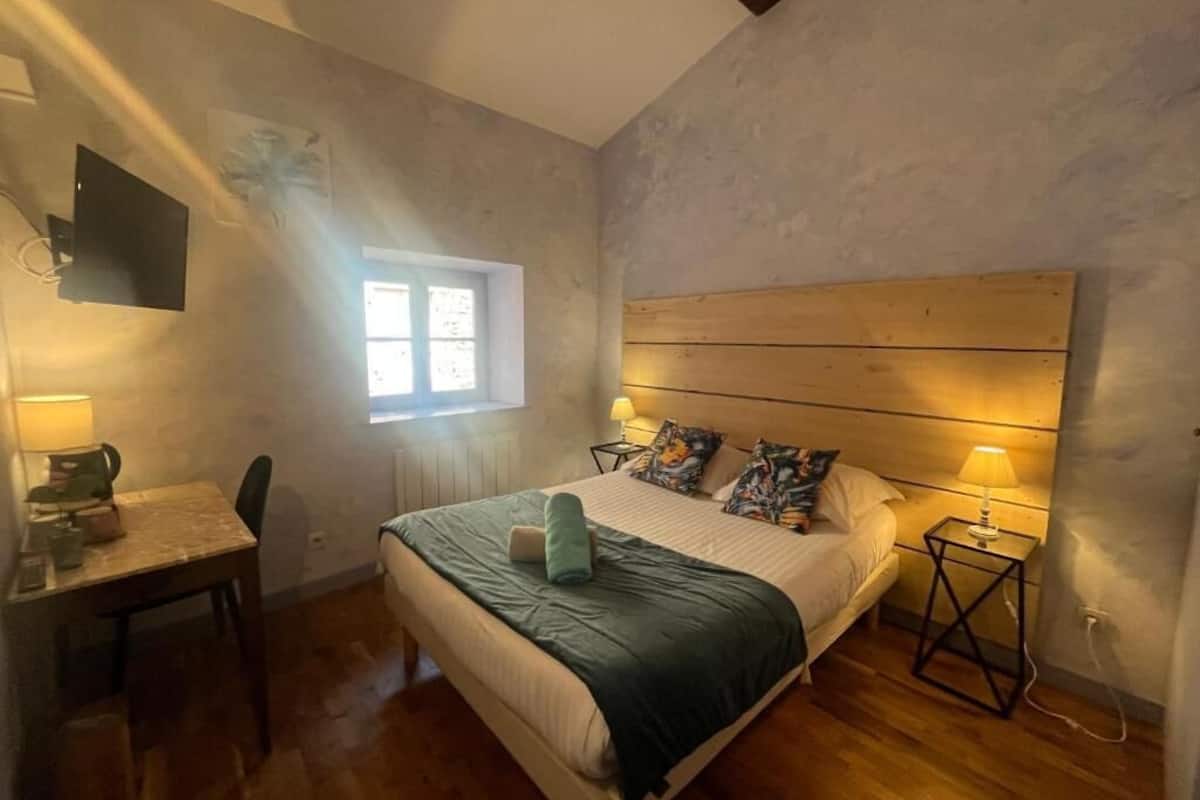 Un dormitorio con cama, lámparas de noche, un escritorio y una silla.