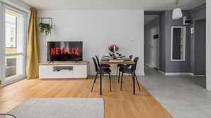 A modern living room with a dining area, a TV displaying 'NETFLIX', and a large window with curtains. - Lumina lux apart in the center of Warsaw (Warsaw)