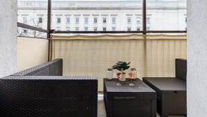 A balcony with wicker furniture, a potted plant, and two wine glasses on a table. - Lumina lux apart in the center of Warsaw (Warsaw)