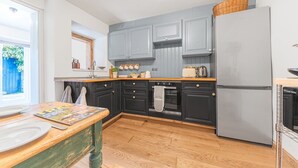 A kitchen with dark cabinets, a refrigerator, and a wooden countertop. - Kirkland Cottage Ennerdale Lake District (Cumbria)